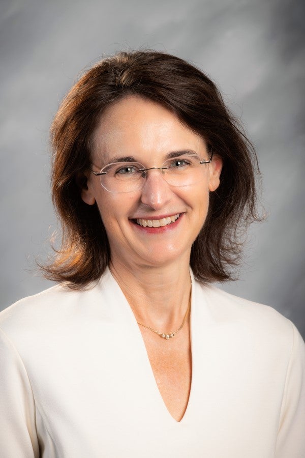 Jennifer Sobanet headshot; white blouse against gray backdrop