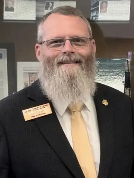 Image of Jon Caudill in a black suite with a gold name badge